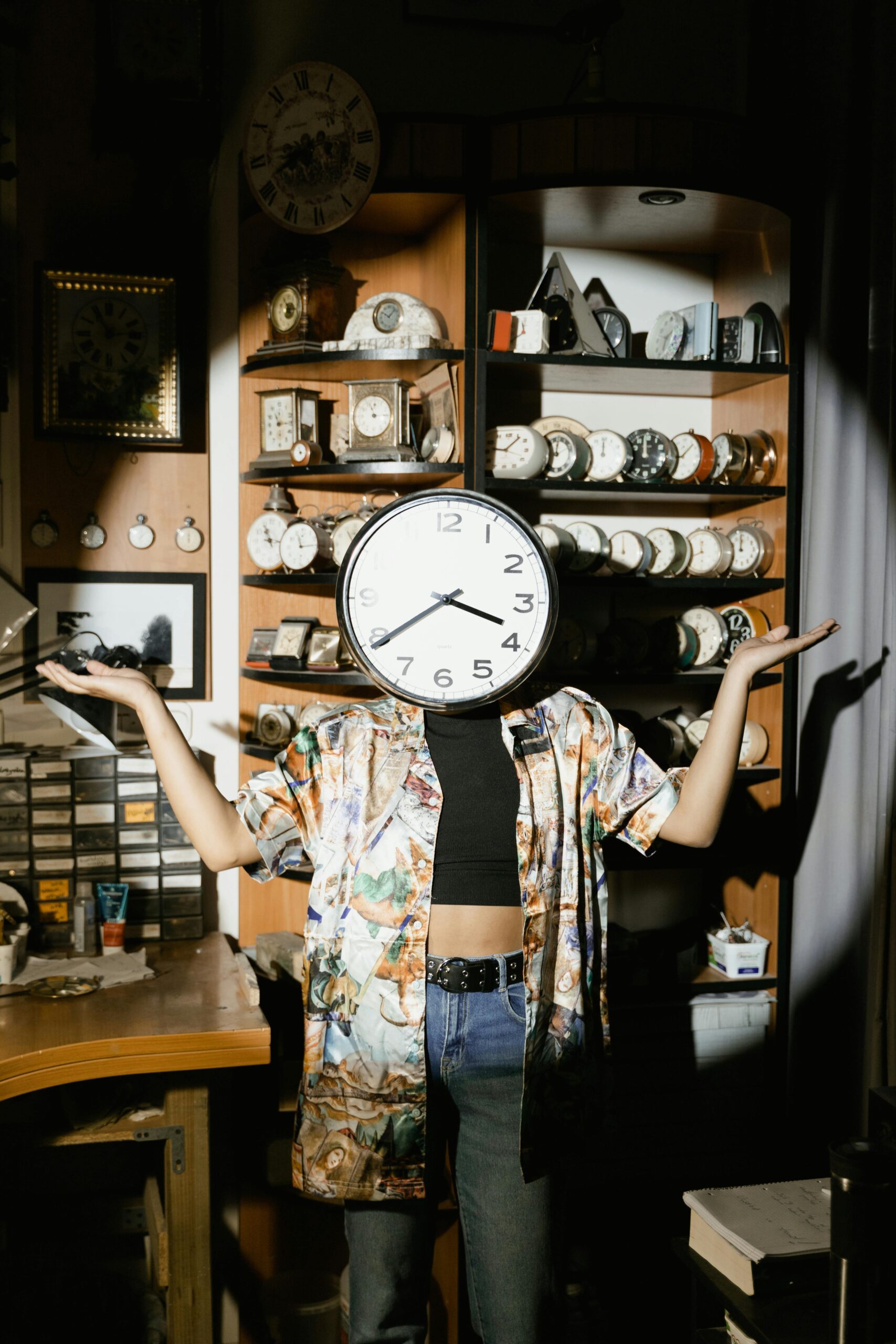 A creative photo of a person with a clock obscuring their face, surrounded by vintage clocks on wooden shelves.